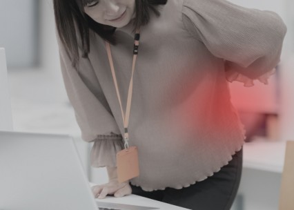 腰を押さえながら前かがみになる女性