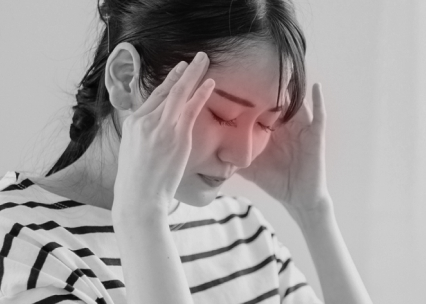 こめかみに手を当てて頭を抱える女性